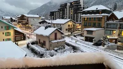 a town covered in snow with buildings and mountains at Studio meublé bon emplacement in Chamonix-Mont-Blanc