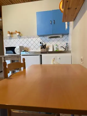 a kitchen with a wooden table and blue cabinets at Studio meublé bon emplacement in Chamonix-Mont-Blanc