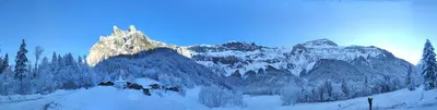 a snow covered mountain with a house in the foreground at Le Refuge des Trolls in Sixt