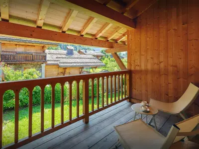 a porch of a cabin with a table and a chair at Chalet Nahuel Huapi - OVO Network in Samoëns