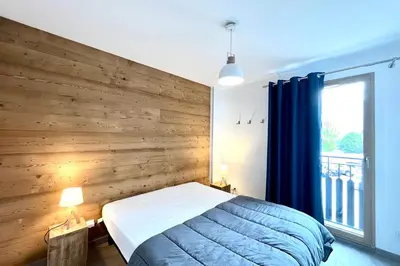 a bedroom with a wooden wall with a bed and a window at Clair des Prés in Saint-Gervais-les-Bains