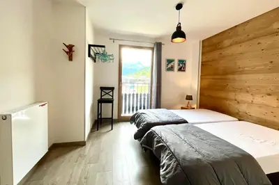 two beds in a bedroom with a wooden wall at Clair des Prés in Saint-Gervais-les-Bains