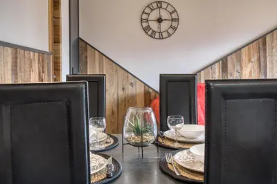 a table with plates and glasses and a clock on the wall at Charmant appartement avec balcon et commodités modernes in Samoëns