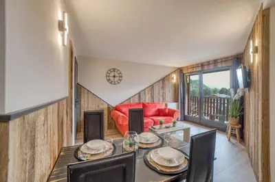 a living room with a table and a red couch at Charmant appartement avec balcon et commodités modernes in Samoëns
