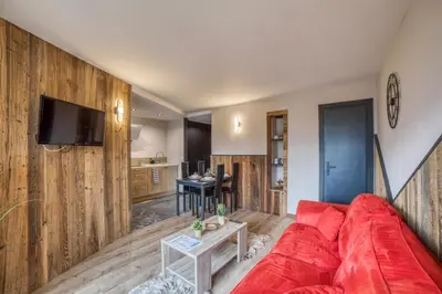 a living room with a red couch and wooden walls at Charmant appartement avec balcon et commodités modernes in Samoëns