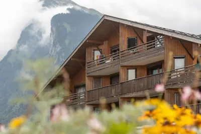 a building with people on the balcony with a mountain at Charmant appartement avec balcon et commodités modernes in Samoëns