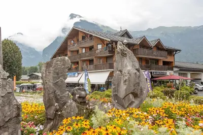 a large rock in a garden in front of a building at Charmant appartement avec balcon et commodités modernes in Samoëns