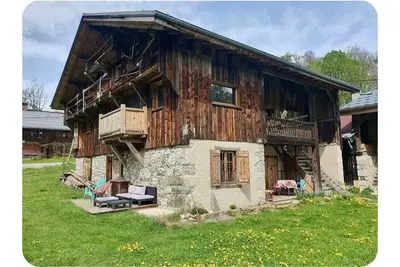 an old wooden house with a bench in front of it at Chalet Combe in Samoëns