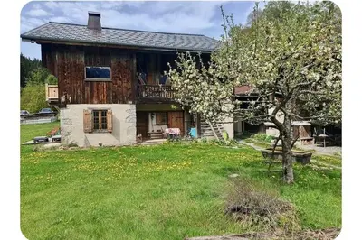 a wooden house with a tree in the yard at Chalet Combe in Samoëns