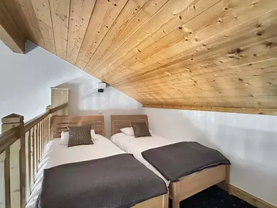 two beds in a room with a wooden ceiling at CRIS112 - Duplex 8 personnes centre village in Les Carroz d'Araches