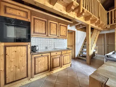 a kitchen with wooden cabinets and a spiral staircase at CRIS112 - Duplex 8 personnes centre village in Les Carroz d'Araches