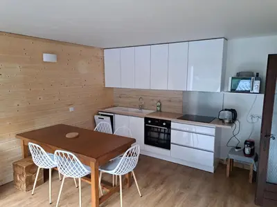a kitchen with white cabinets and a wooden table and chairs at T3 avec vue montagne in Les Contamines-Montjoie