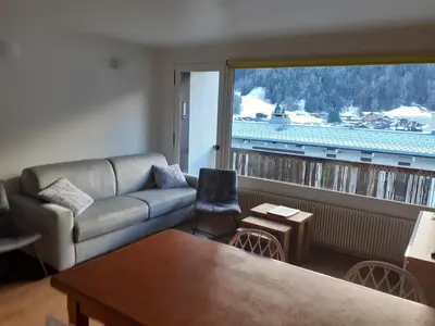 a living room with a couch and a large window at T3 avec vue montagne in Les Contamines-Montjoie