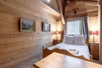 a bedroom in a log cabin with a bed and a table at Le Gite - Le Mont Blanc - 9 pax in Saint-Gervais-les-Bains