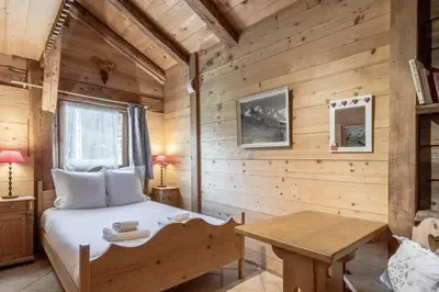 a bedroom in a log cabin with a bed and a table at Le Gite - Le Mont Blanc - 9 pax in Saint-Gervais-les-Bains