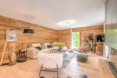 a living room with wooden walls and a couch and chairs at Appartement Capra - Welkeys in Megève