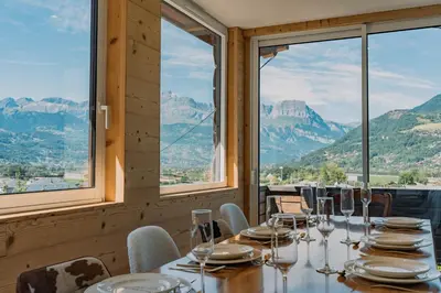 a table in a restaurant with a view of mountains at Au pied du télécabine & gare St Gervais in Saint-Gervais-les-Bains