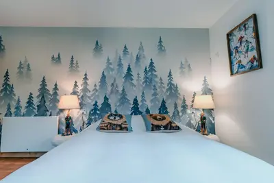 a bedroom with a white bed with trees on the wall at Au pied du télécabine & gare St Gervais in Saint-Gervais-les-Bains