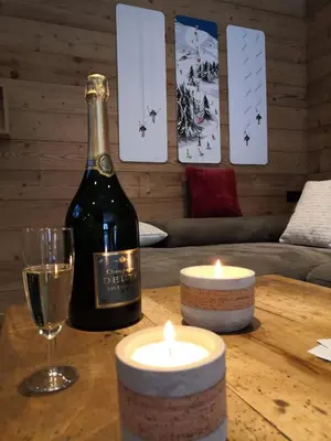 a bottle of wine and candles on a wooden table at Chalet Josaly Jacuzzi et Sauna in Samoëns