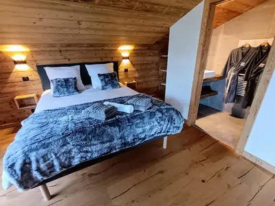 a bedroom with a bed and a wooden wall at Chalet Josaly Jacuzzi et Sauna in Samoëns