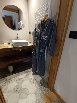 a bathroom with a robe hanging on the wall at Chalet Josaly Jacuzzi et Sauna in Samoëns