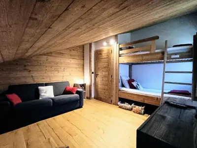 a living room with a couch and a bunk bed at Chalet Josaly Jacuzzi et Sauna in Samoëns