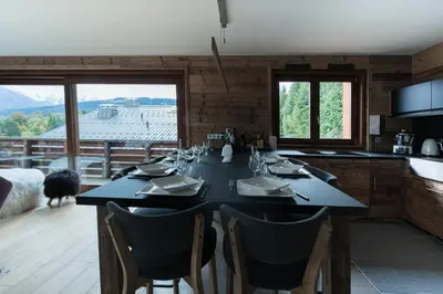 a dining room with a table with chairs and a kitchen at Chaleureux Chalet Familial - Vue époustouflante in Combloux