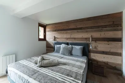 a bedroom with a wooden wall and a bed at Chaleureux Chalet Familial - Vue époustouflante in Combloux