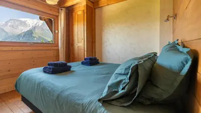 a bedroom with a bed with blue sheets and a window at Chalet Vallée de Chamonix, Ski, Snow, Spa vue MontBlanc by ImmoConciergerie in Saint-Gervais-les-Bains
