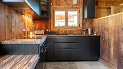 a kitchen with black cabinets and a sink at Chalet Vallée de Chamonix, Ski, Snow, Spa vue MontBlanc by ImmoConciergerie in Saint-Gervais-les-Bains