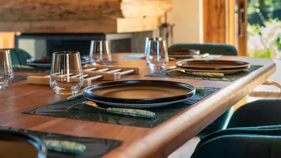a wooden table with plates and glasses on it at Chalet Vallée de Chamonix, Ski, Snow, Spa vue MontBlanc by ImmoConciergerie in Saint-Gervais-les-Bains
