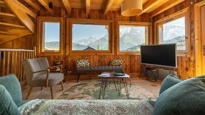 a living room with a couch and a tv and windows at Chalet Vallée de Chamonix, Ski, Snow, Spa vue MontBlanc by ImmoConciergerie in Saint-Gervais-les-Bains