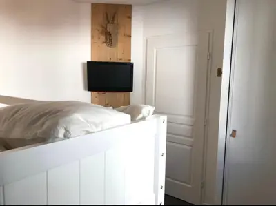 a bedroom with a white bed with a tv on it at Appartement à 20m des pistes, avec piscine et sauna in Arâches-la-Frasse