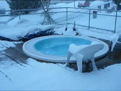 a hot tub covered in snow in a yard at Appartement à 20m des pistes, avec piscine et sauna in Arâches-la-Frasse