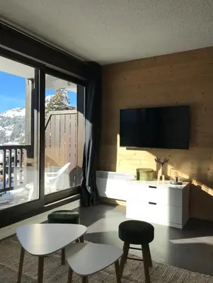 a living room with a flat screen tv on a wall at Appartement à 20m des pistes, avec piscine et sauna in Arâches-la-Frasse