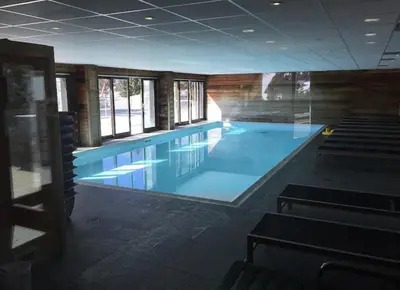 a large swimming pool in a building with windows at Appartement à 20m des pistes, avec piscine et sauna in Arâches-la-Frasse