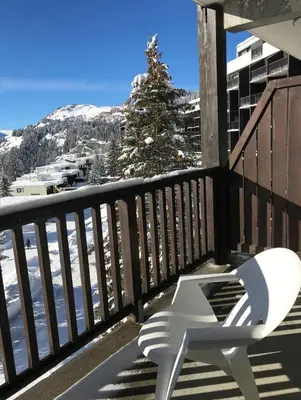 a white chair on a balcony with a snow covered mountain at Appartement à 20m des pistes, avec piscine et sauna in Arâches-la-Frasse