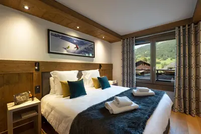 a bedroom with a large bed with two towels on it at MGM Hôtels & Résidences - Hôtel Laska in Les Contamines-Montjoie