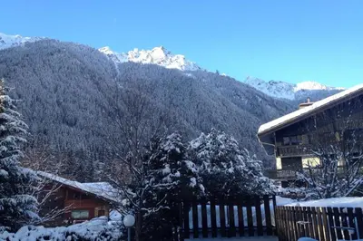 a house with a snow covered mountain in the background at Beautiful T2 with balcony near track in Chamonix-Mont-Blanc