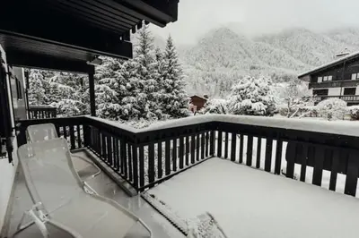 a snow covered balcony with a table and chairs at Beautiful T2 with balcony near track in Chamonix-Mont-Blanc