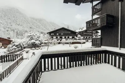 a snow covered balcony of a house with a building at Beautiful T2 with balcony near track in Chamonix-Mont-Blanc