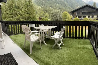 a patio with a table and chairs on the grass at Beautiful T2 with balcony near track in Chamonix-Mont-Blanc