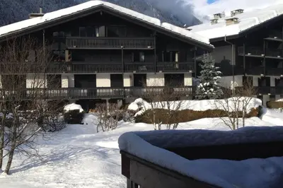 a large building with snow in front of it at Beautiful T2 with balcony near track in Chamonix-Mont-Blanc