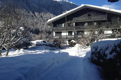 a ski lodge with a snow covered yard in front at Beautiful T2 with balcony near track in Chamonix-Mont-Blanc