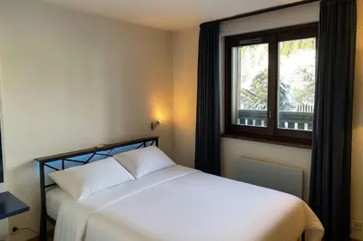 a bedroom with a white bed and a window at Beautiful T2 with balcony near track in Chamonix-Mont-Blanc