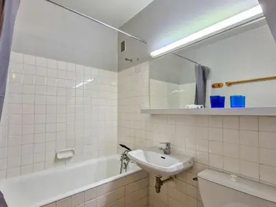 a white tiled bathroom with a sink and a bath tub at Studio lumineux avec balcon - Proche des pistes et commerces - FR-1-425-226 in Arâches-la-Frasse