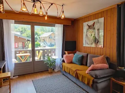 a living room with a couch and a sliding glass door at Appartement vue Montblanc 5mn piste2 in Les Trabets
