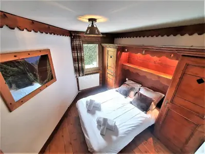 a bedroom with a bed in the corner of a room at La Ginabelle – vue Mont Blanc avec piscine in Chamonix-Mont-Blanc