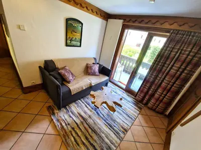 a living room with a couch and a large window at La Ginabelle – vue Mont Blanc avec piscine in Chamonix-Mont-Blanc