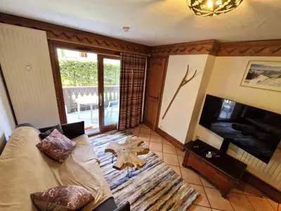 a living room with a couch and a television at La Ginabelle – vue Mont Blanc avec piscine in Chamonix-Mont-Blanc